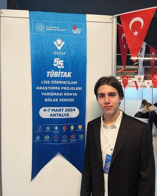 Demir next to the TÜBİTAK exhibition banner